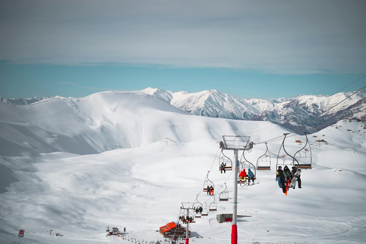 Persone su una seggiovia che sale su un pendio montano innevato.