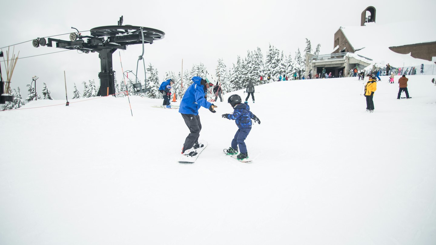 Maestro di snowboard insegna a un bambino su un pendio di montagna.