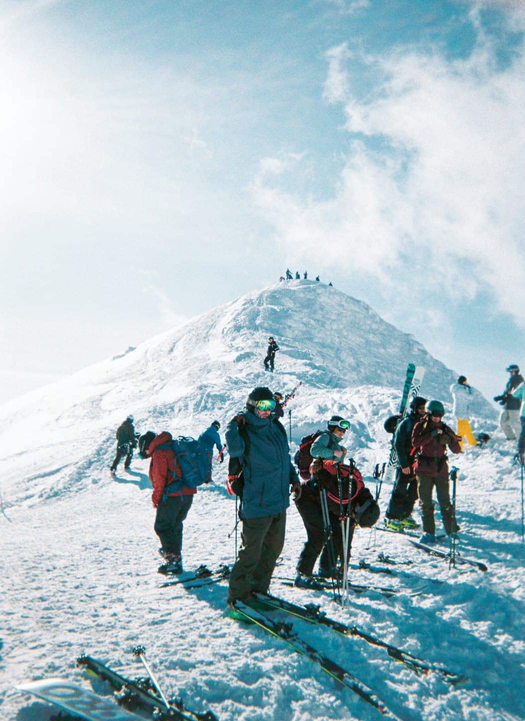 Sciatori e snowboarder si radunano sulla cima di una montagna innevata.