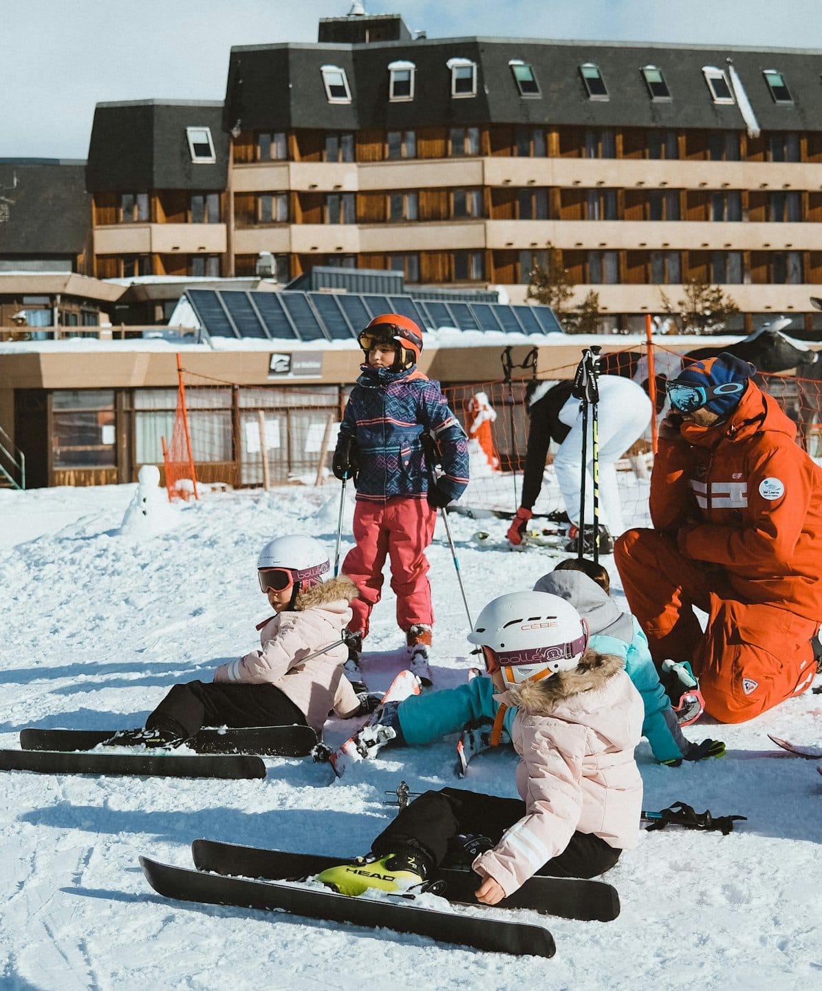 Bambini in tenuta da sci che imparano a sciare con istruttori su una pista.